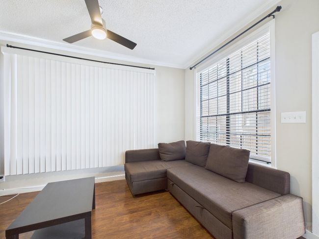 Living area with crown molding, dark wood-type flooring, a textured ceiling, and a ceiling fan | Image 7