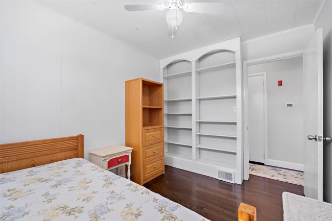 Bedroom with dark wood-style floors, a ceiling fan, visible vents, and crown molding | Image 28