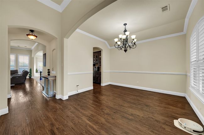 Dining space featuring ornamental molding, dark wood-type flooring, a chandelier, and arched walkways | Image 33