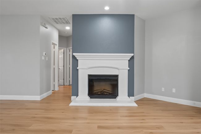 Unfurnished living room featuring light wood-type flooring, a fireplace with raised hearth, baseboards, and recessed lighting | Image 15