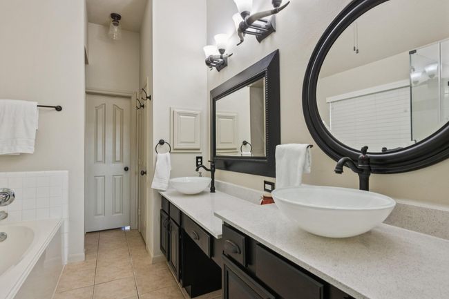 Primary bathroom offers double sinks and a vanity. Notice the custom light fixtures. | Image 24