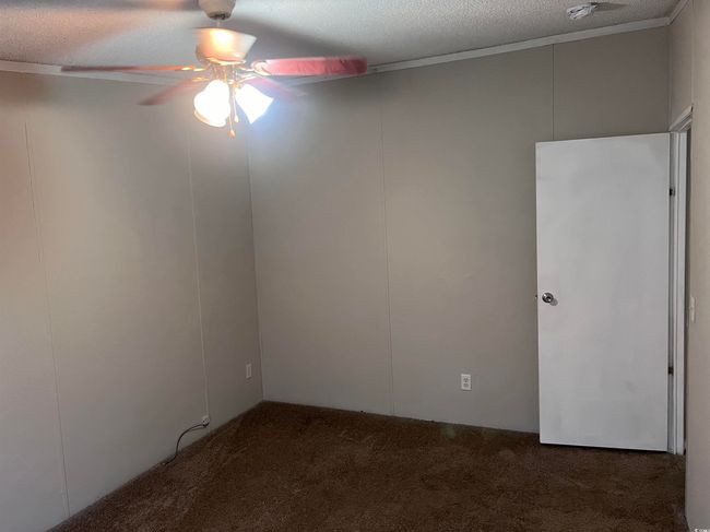 Spare room featuring ceiling fan, carpet floors, and a textured ceiling | Image 16