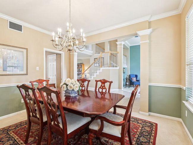 Dining area with ornamental molding, stairs, a chandelier, baseboards, and ornate columns | Image 13