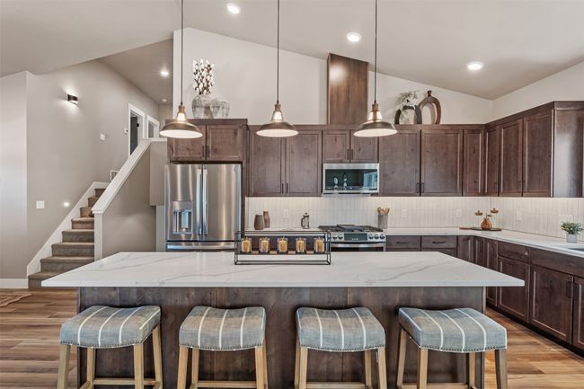 Kitchen featuring appliances with stainless steel finishes, light wood-type flooring, backsplash, dark brown cabinetry, and a kitchen breakfast bar | Image 44