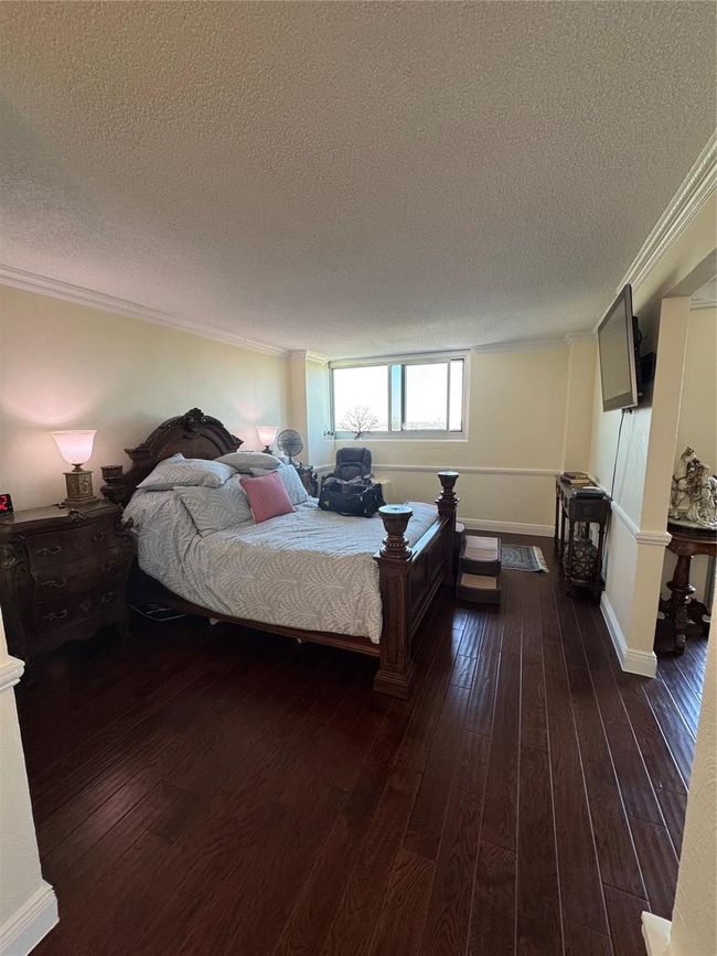 Bedroom featuring a textured ceiling, ornamental molding, and dark wood finished floors | Image 7