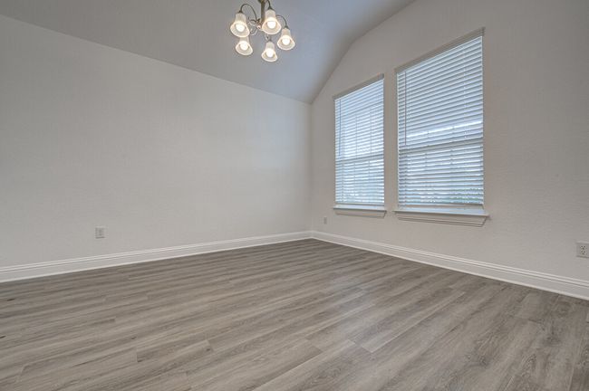 Empty room featuring vaulted ceiling, a chandelier, wood finished floors, and baseboards | Image 4
