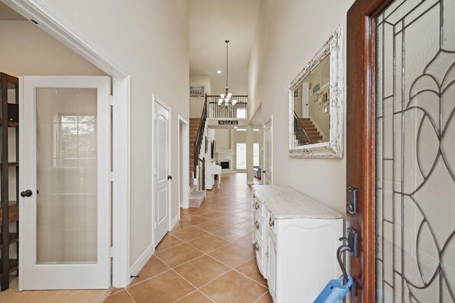 Welcome to a bright, inviting entryway with high ceilings and tile flooring. The space features a glass-panel door leading to an adjacent room. Ample natural light enhances this spacious and welcoming foyer. | Image 5