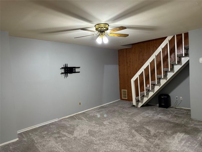 Carpeted spare room featuring baseboards, stairway, visible vents, and a ceiling fan | Image 9