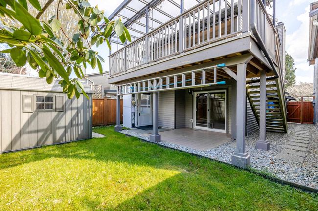 Rear view of house featuring stairs, a patio area, an outdoor structure, a fenced backyard, and a yard | Image 6