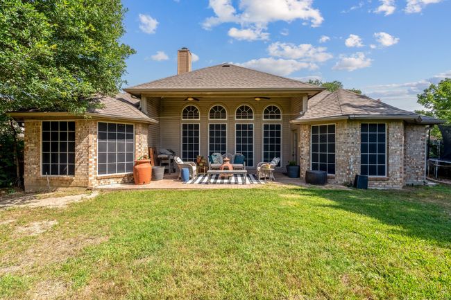 Rear view of property featuring a patio, a chimney, a yard, and a shingled roof | Image 37