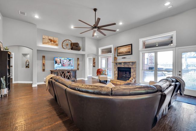 Living room with a fireplace, dark wood-type flooring, and ceiling fan | Image 8