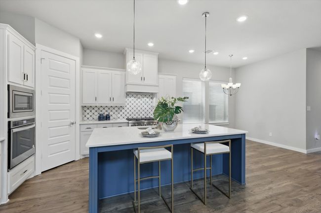 Kitchen with stainless steel appliances, a center island, white cabinets, tasteful backsplash, and dark wood finished floors | Image 7