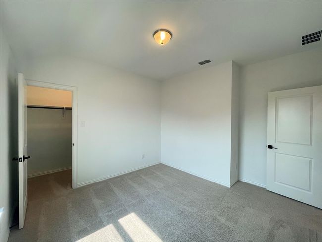 Unfurnished bedroom with carpet floors, a walk in closet, and a closet | Image 20
