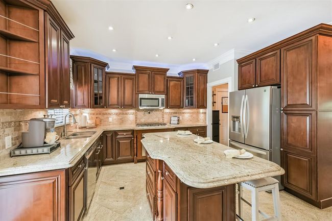 Spacious island seating with sleek stainless steel appliances. | Image 12