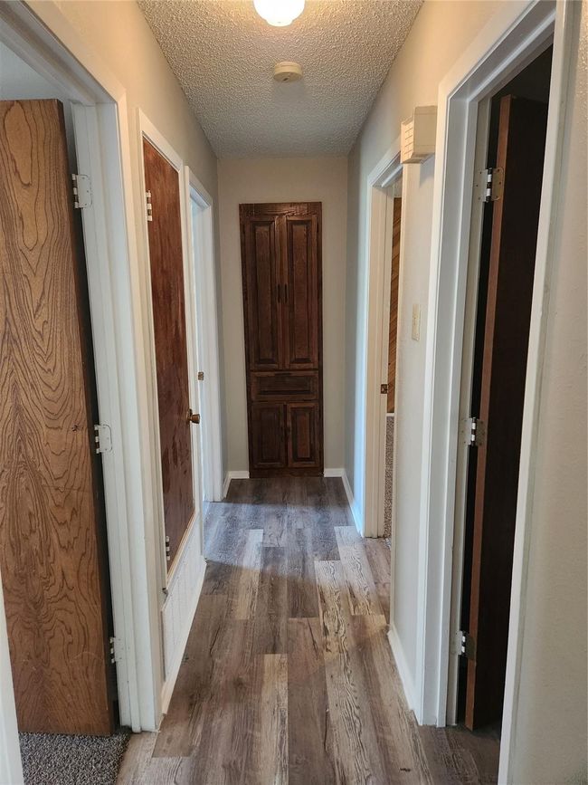Hall featuring wood finished floors, a textured ceiling, and baseboards | Image 12