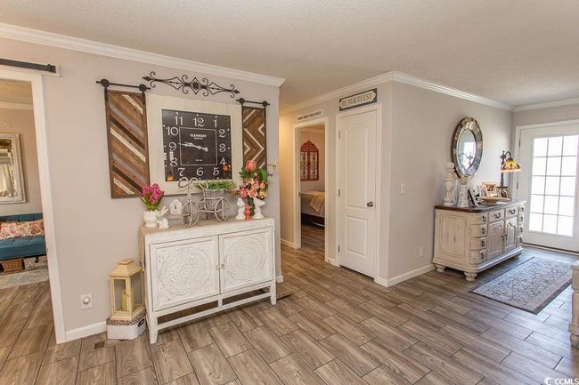 Foyer featuring wood finished floors, ornamental molding, baseboards, visible vents, and a textured ceiling | Image 4