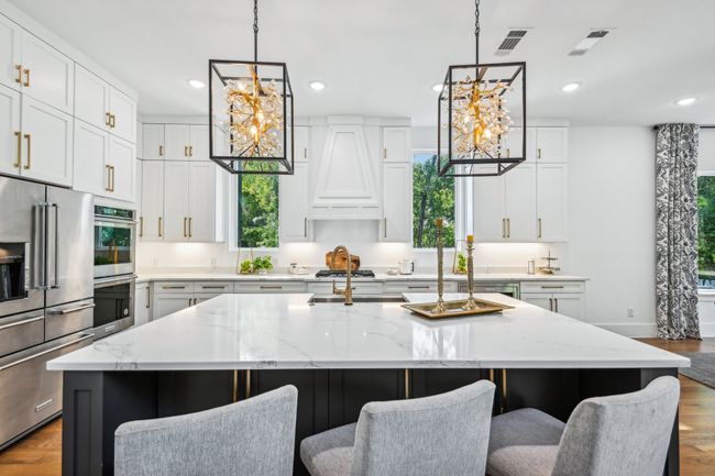 Kitchen with a chandelier, stainless steel appliances, a center island with sink, wood finished floors, and recessed lighting | Image 13