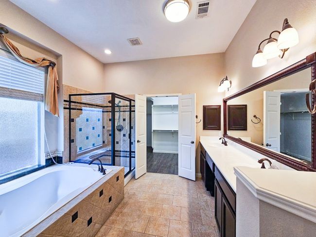 Bathroom featuring a shower stall, a spacious closet, a garden tub, double vanity, and tile patterned flooring | Image 14