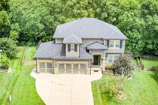 French country home with an attached garage, stone siding, roof with shingles, and driveway | Image 51