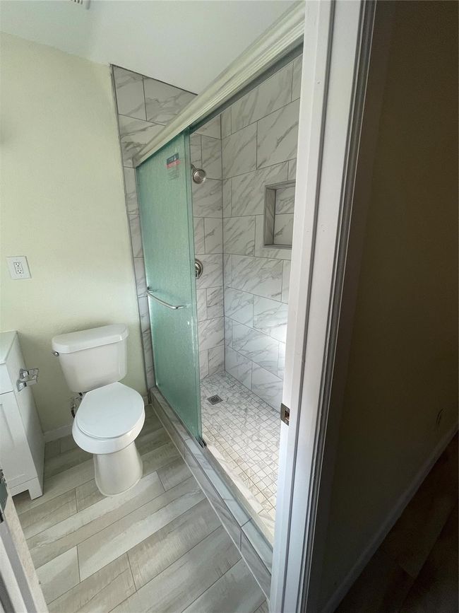 Bathroom with toilet, a shower stall, and baseboards | Image 11
