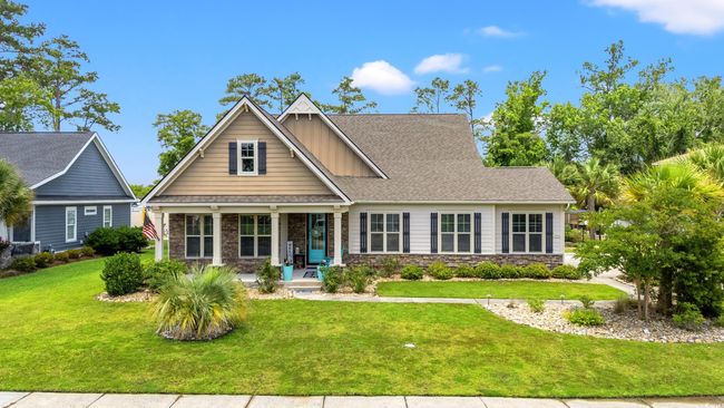 Craftsman-style house with covered porch, a front yard, stone siding, and roof with shingles | Image 38