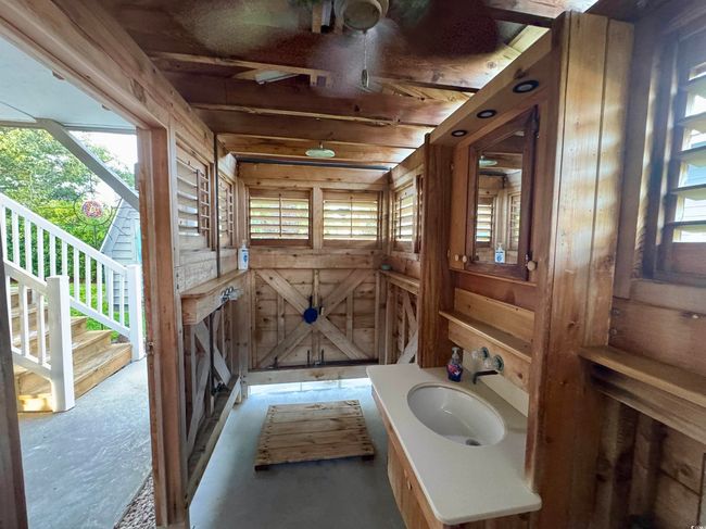 Bathroom featuring plenty of natural light, wooden walls, and vanity | Image 10
