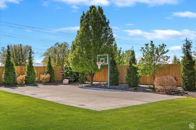 View of basketball court featuring a lawn, fence, and basketball hoop | Image 58