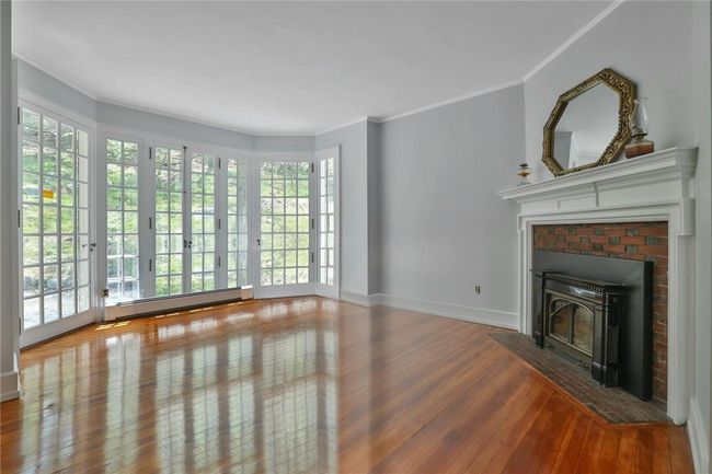 Unfurnished living room with a brick fireplace, crown molding, hardwood / wood-style floors, and a baseboard heating unit | Image 12