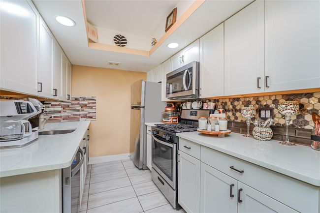 Kitchen with white cabinetry, appliances with stainless steel finishes, tasteful backsplash, and light stone counters | Image 27