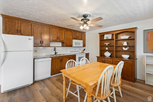 Kitchen featuring white appliances, a ceiling fan, wood finished floors, open shelves, and tasteful backsplash | Image 5