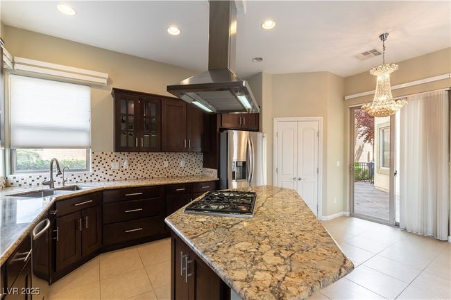 Kitchen with decorative backsplash, island exhaust hood, dark brown cabinets, appliances with stainless steel finishes, and a​​‌​​​​‌​​‌‌​‌‌​​​‌‌​​‌‌​‌​​​​​‌ sink | Image 5