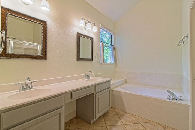 Full bath featuring a bath, tile patterned floors, double vanity, vaulted ceiling, and a shower with shower door | Image 21