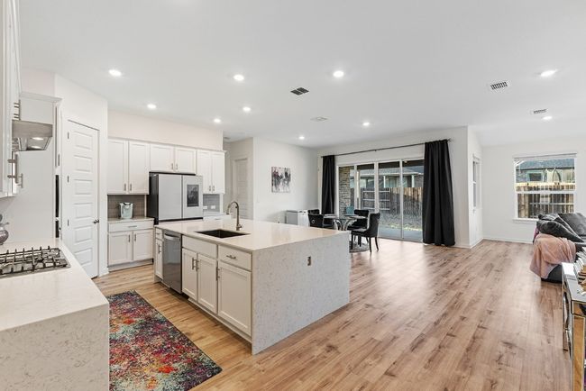 Kitchen with a sink, stainless steel appliances, visible vents, and light wood-style flooring | Image 10