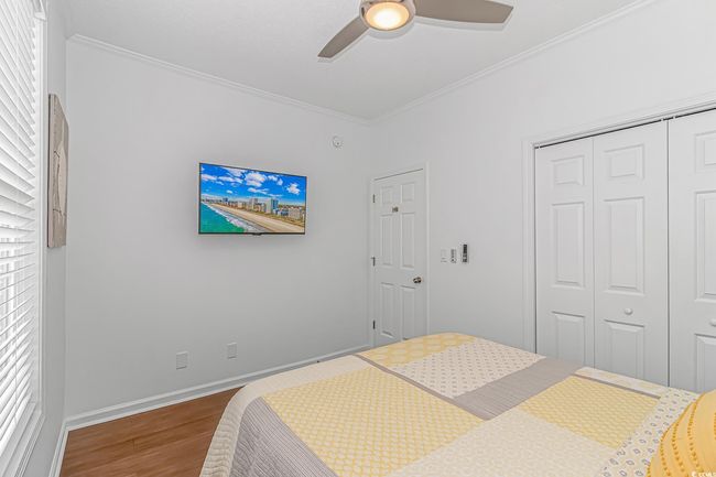 Bedroom with wood finished floors, a closet, ornamental molding, a ceiling fan, and baseboards | Image 22