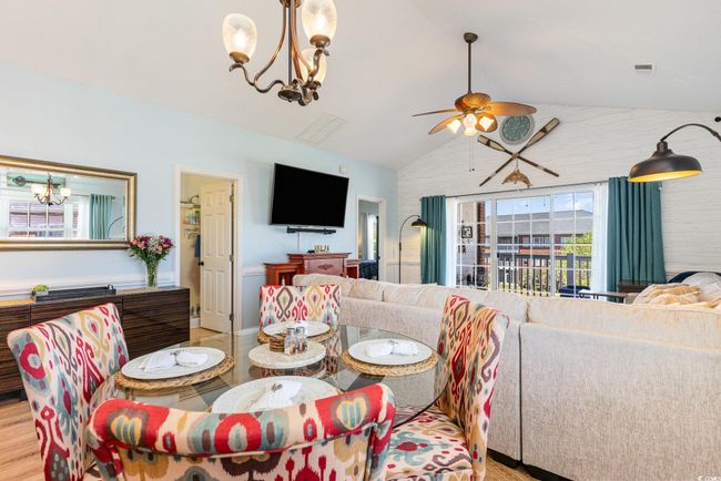 Dining space featuring ceiling fan with notable chandelier, light wood-style flooring, and vaulted ceiling | Image 9