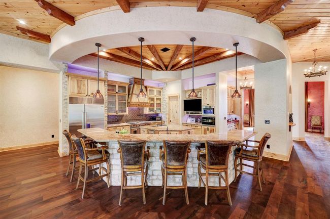 The wagon wheel wood features draw the eye into the rustic stone and wood driven kitchen. | Image 15