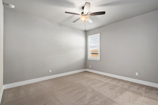Spare room featuring light carpet, ceiling fan, and a smoke detector | Image 23