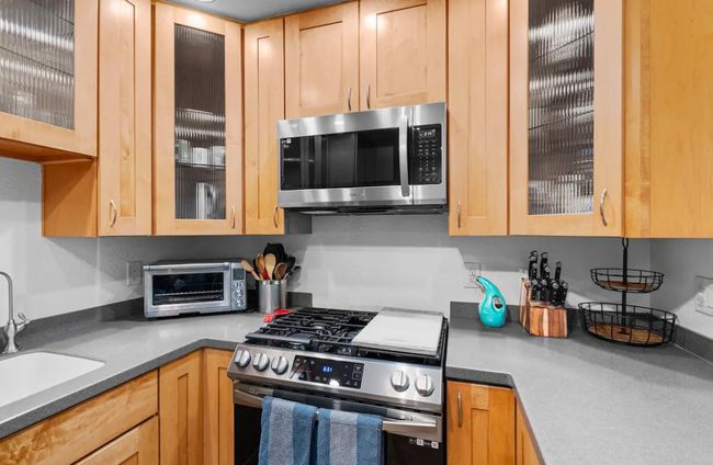 Kitchen featuring appliances with stainless steel finishes, glass insert cabinets, and light brown cabinetry | Image 9