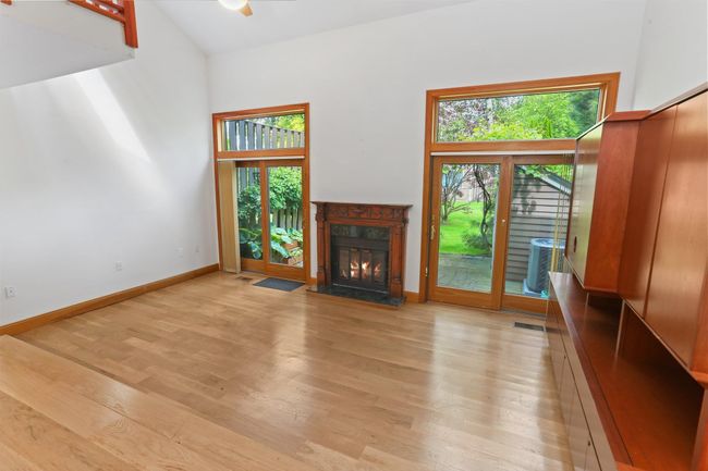 Unfurnished living room featuring light wood-type flooring, a fireplace, a high ceiling, and baseboards | Image 14