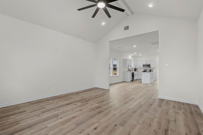 Unfurnished living room featuring high vaulted ceiling, beamed ceiling, ceiling fan, and light hardwood / wood-style flooring | Image 4