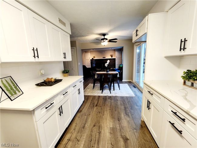 Kitchen with light stone counters, ceiling fan, white cabinets, and dark hardwood / wood-style flooring | Image 6