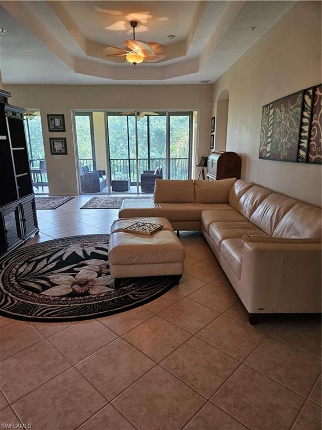 Tiled living room with ceiling fan and a raised ceiling | Image 11