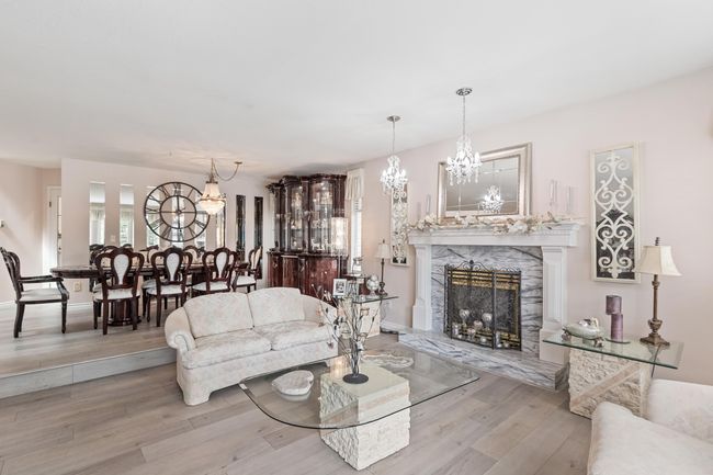 Living room with a fireplace, wood finished floors, and a chandelier | Image 9