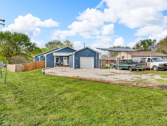 single story home with a front lawn, gravel driveway, a garage, and fence | Image 24