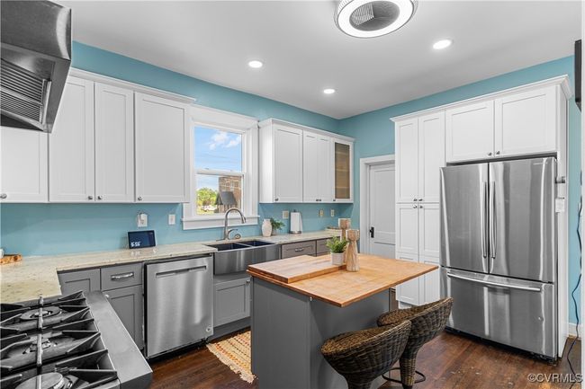 Kitchen with stainless steel appliances, a sink, dark wood-style flooring, range hood, and butcher block counters | Image 17