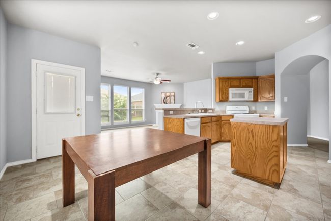 Kitchen featuring white appliances, arched walkways, light countertops, a center island, and a peninsula | Image 5