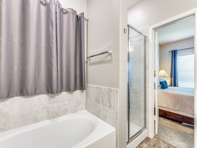 Bathroom with ensuite bathroom, a garden tub, a shower stall, and a textured wall | Image 21