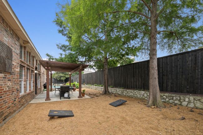 A charming pergola anchors the outdoor living area with stone pavers, garden beds, and space for grilling and dining al fresco. | Image 31