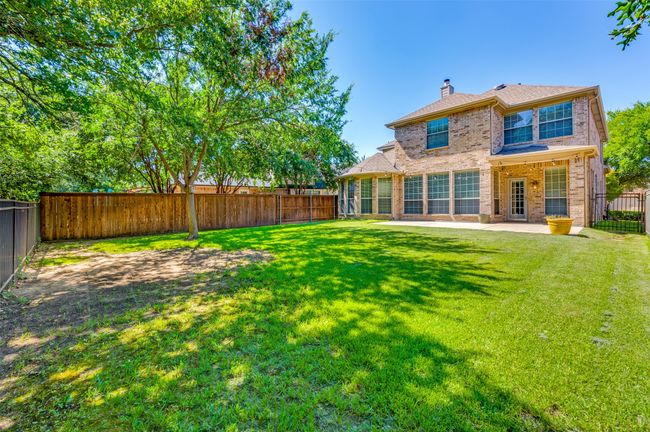 Rear view of house with brick siding, a fenced backyard, and open & covered patio | Image 25