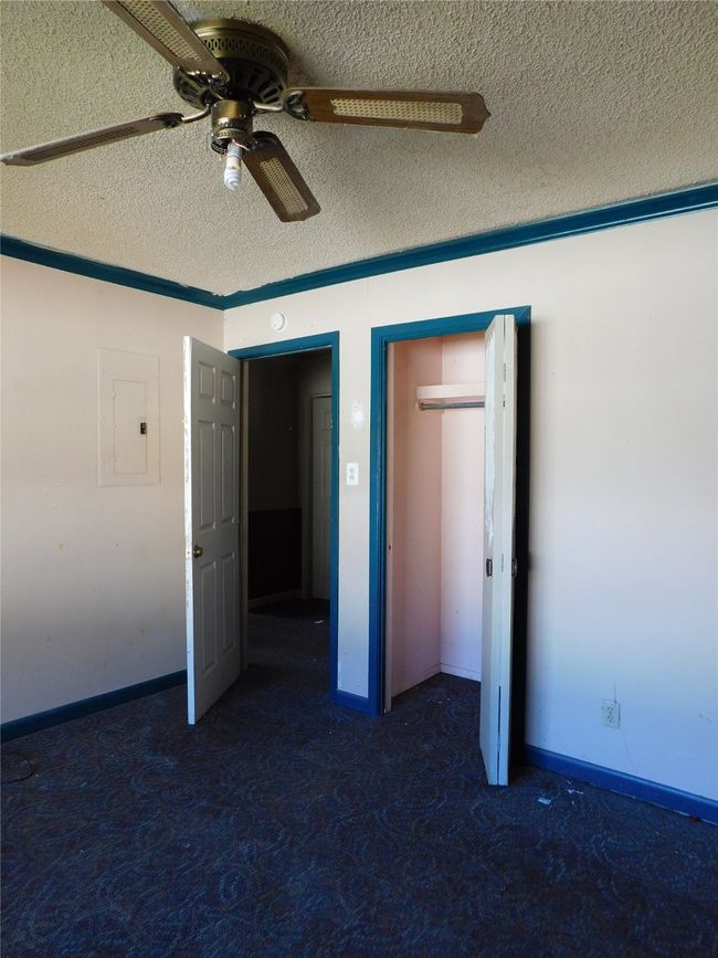 Unfurnished bedroom with dark colored carpet, a textured ceiling, electric panel, and ceiling fan | Image 26